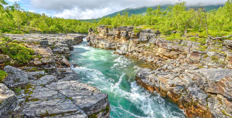 Ein reisender Fluss fließt durch einen Schlucht im Abisko Nationalpark