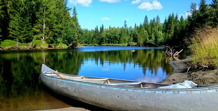 Ein leeres Kanu liegt an einem Flussufer in Schweden