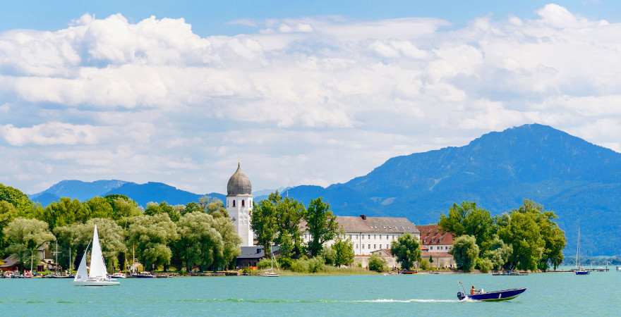 Eine Kirche auf einer Insel im See vor Alpenpanorama