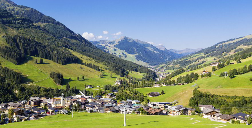 Schöne Aussicht auf das österreichische Dorf Saalbach und einige grüne Felder in den Alpen im Sommer.