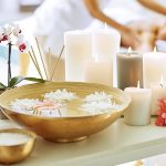 Ausschnitt aus verschiedenen Verwöhnprodukten in einem Spa mit einer Frau, die im Hintergrund eine Schönheitsbehandlung erhält