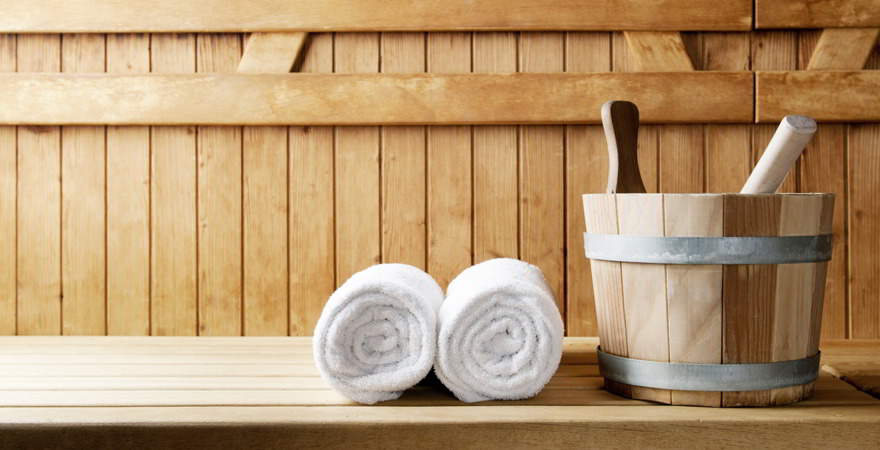 Detail von Eimer und weißen Handtüchern in einer Sauna.