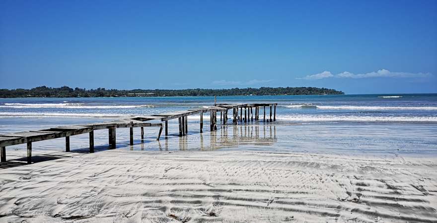 ein zerfallen Holzsteg an einem unberührten Strand