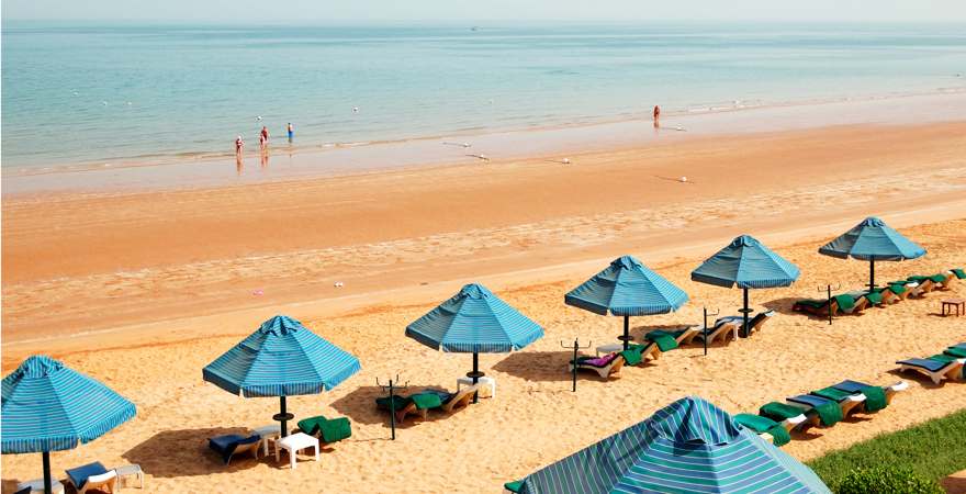 Sandstrand mit blauen sonnenschirmem