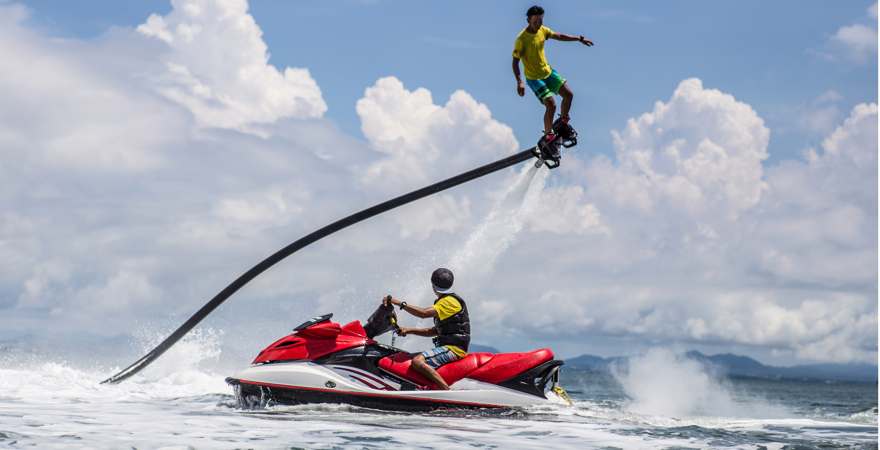 Mann auf Flxyboard schwebt über einem Jetski