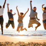 fünf Menchen machen einen Freudensprung am Strand