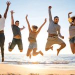 Fröhliche junge Menschen springen am strand in die luft