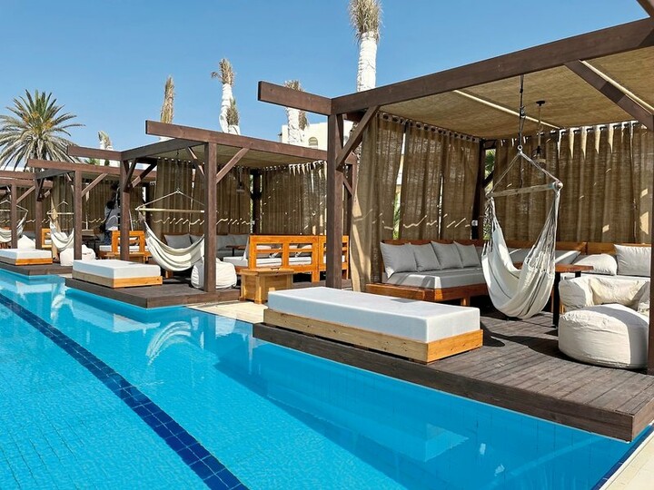 Ein luxuriöser Pool mit Liegen und Hängematten, ideal zum Entspannen am Wasser in einem eleganten Hotel.