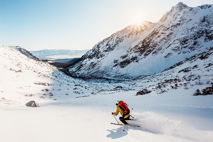 Ein Skifahrer gleitet elegant die schneebedeckte Berglandschaft hinunter, während die Sonne auf die Piste scheint.