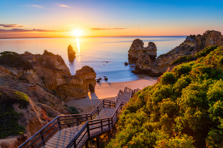 Sonnenuntergang über der Algarve, Portugal, mit warmen Farben, die den Himmel und das Meer erleuchten.