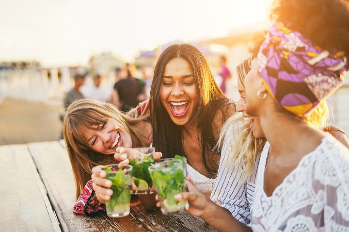 Vier Frauen genießen Cocktails auf einer fröhlichen Party.
