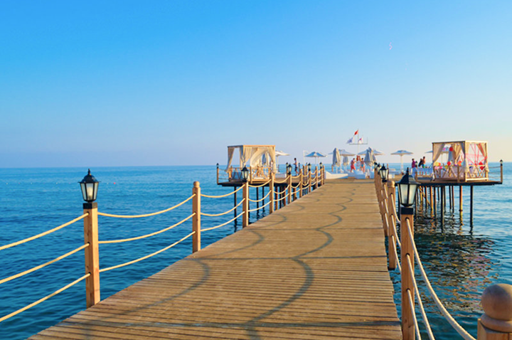 Ein Holzsteg mit bunten Sonnenschirmen und Liegen, ideal für entspannte Tage am Wasser.