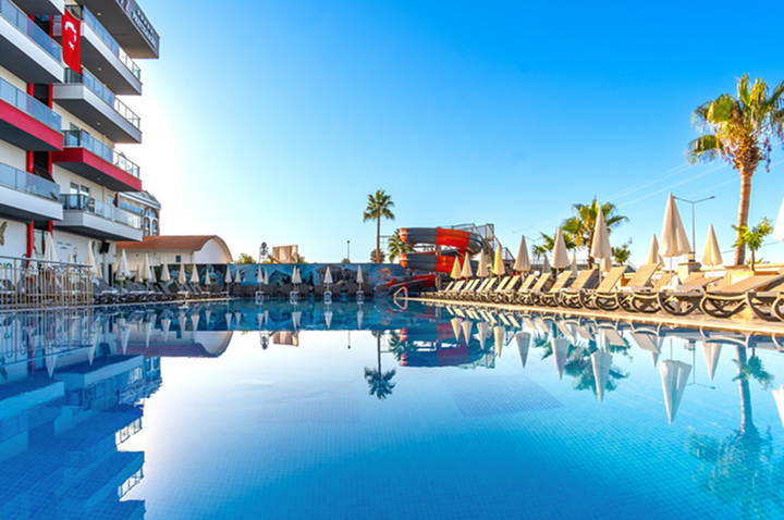 Entspannender Poolbereich mit Liegen und Schirmen vor einem Hotel, perfekt für einen sonnigen Tag.