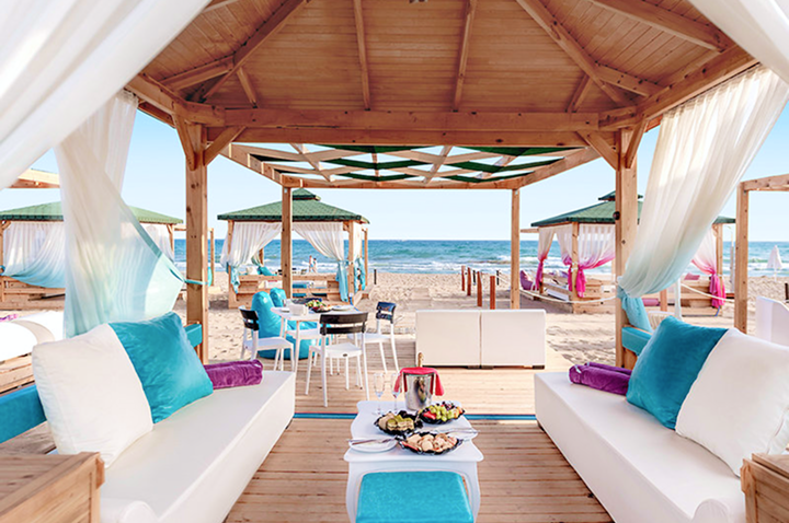 Ein Strand mit einem Pavillon und einem Tisch mit Stühlen, ideal für Gäste eines Hotels, die entspannen möchten.