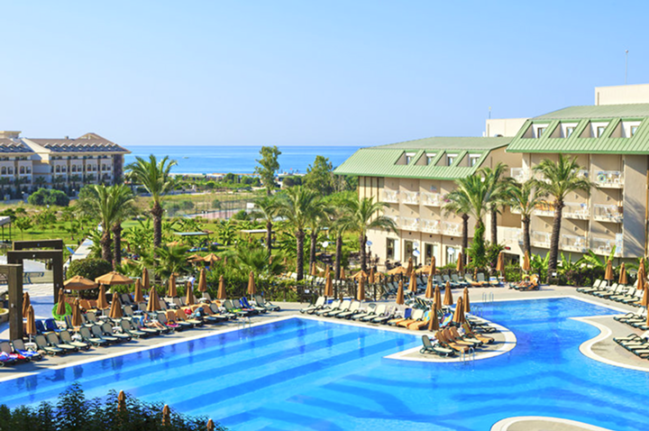 Weitläufiger Pool mit Lounge-Stühlen und Sonnenschirmen, perfekt für Erholung im Hotel am Strand.