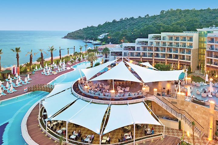 Blick auf ein Hotelresort mit einem glitzernden Pool und einem malerischen Strandbereich, perfekt für einen Urlaub.