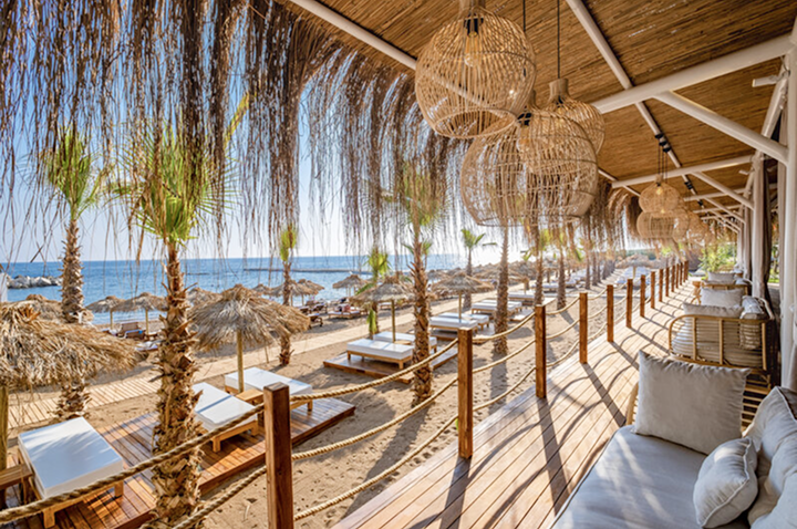 Strandansicht mit bequemen Liegen und bunten Sonnenschirmen, perfekt für Hotelgäste.