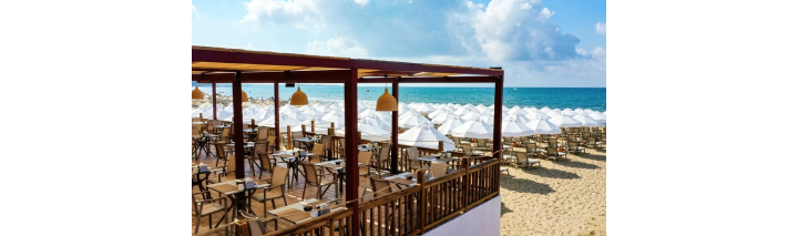 Strandrestaurant eines Hotels in der Türkei mit Sonnenschirmen und Tischen auf dem Sandstrand