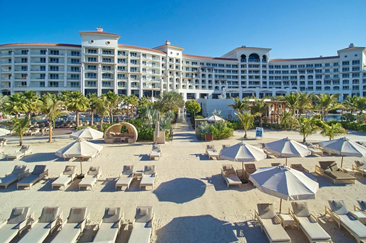 Strandansicht des Hotels in Dubai mit feinem Sand und sanften Wellen unter einem klaren Himmel.