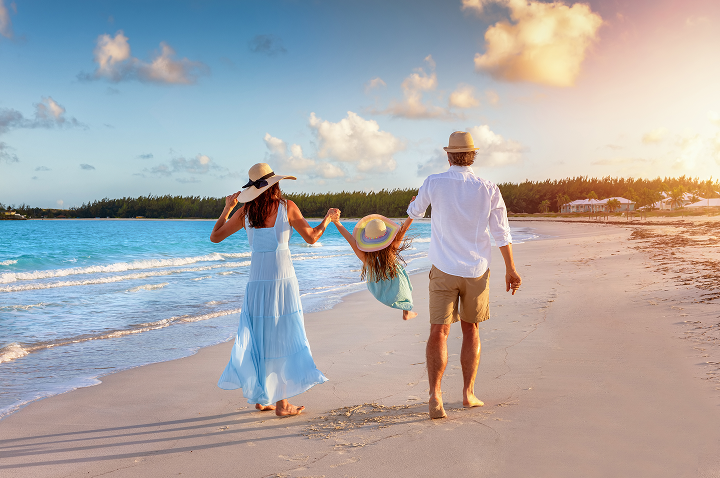 Eine Familie spaziert am Strand bei Sonnenuntergang, während der Himmel in warmen Farben leuchtet.
