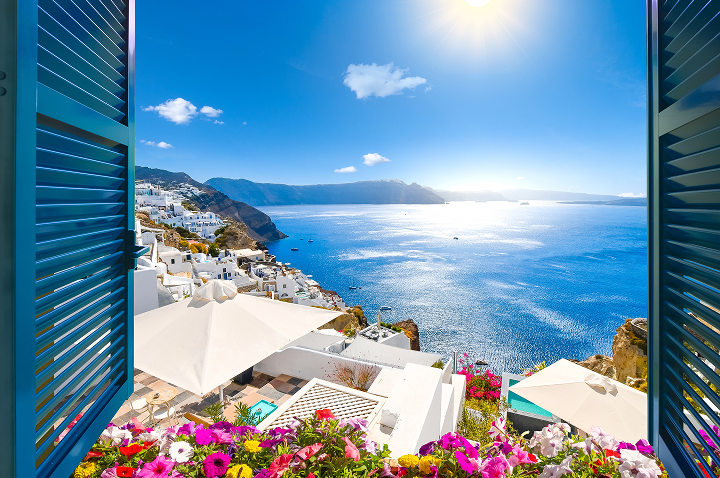 Blick auf das Meer und die Sonne durch das Fenster einer Villa in Santorin, Griechenland.