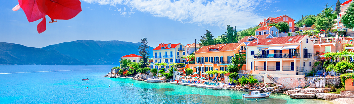 Wunderschöner Blick auf eine griechische Stadt am Wasser, umgeben von sanften Hügeln und strahlend blauem Himmel.