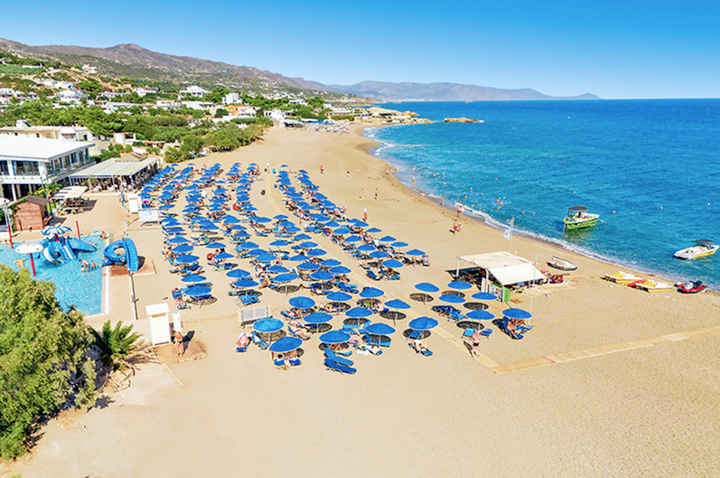 Ein Strand mit zahlreichen Sonnenschirmen und Liegen, ideal für einen entspannten Tag am Meer.
