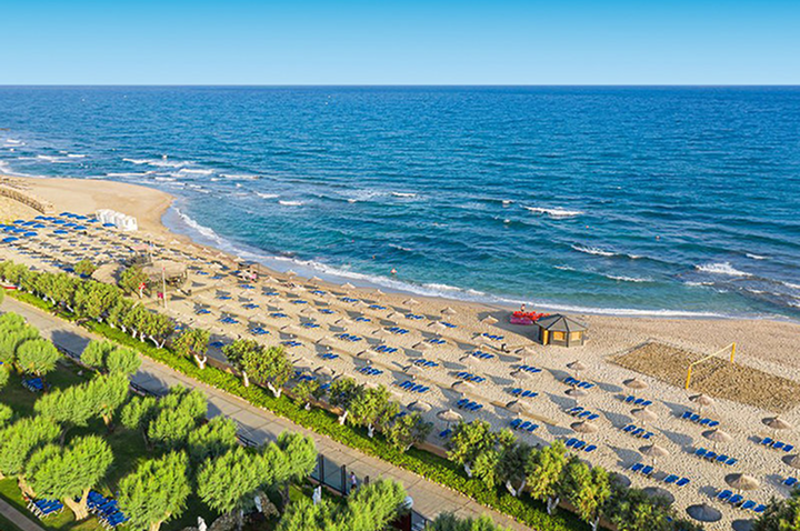 Einladender Hotelstrand mit Liegen und bunten Schirmen, ideal zum Entspannen.