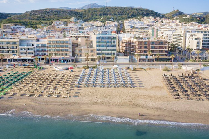Luftaufnahme des Strandes und der Stadt in Kreta, mit Blick auf das Hotel und die umliegende Küstenlandschaft.