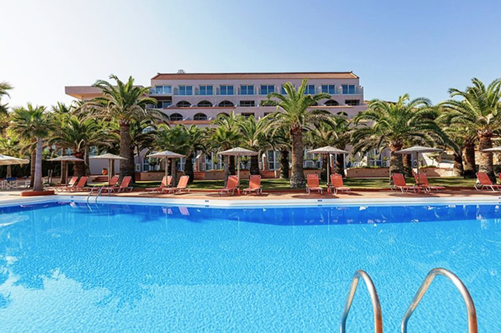 Ein Hotelpool mit Liegen und Sonnenschirmen, umgeben von einer einladenden, sonnigen Atmosphäre.
