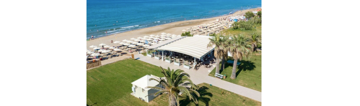 Privater Strand eines Hotels auf Kreta mit Sonnenschirmen und Liegen auf dem Gras, umgeben von klarem Wasser.