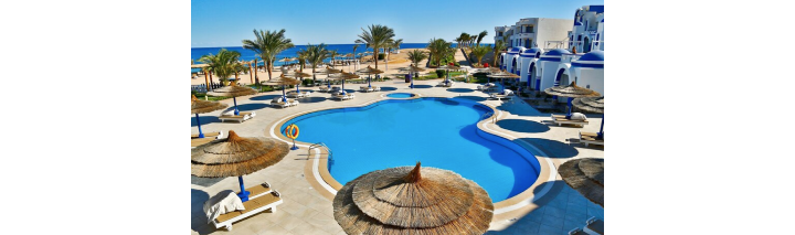 Blick auf den Pool im Hotel Hurghada, umgeben von Palmen und mit Blick auf den Strand.