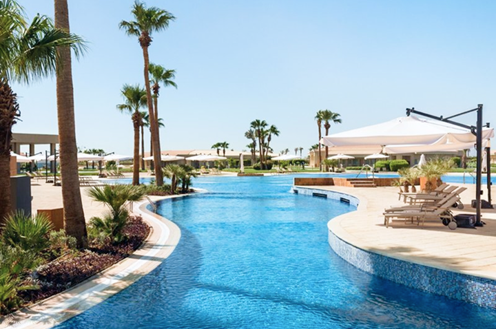 Resort-Pool mit stilvollen Liegen und schattenspendenden Schirmen, umgeben von einer einladenden Urlaubsatmosphäre.