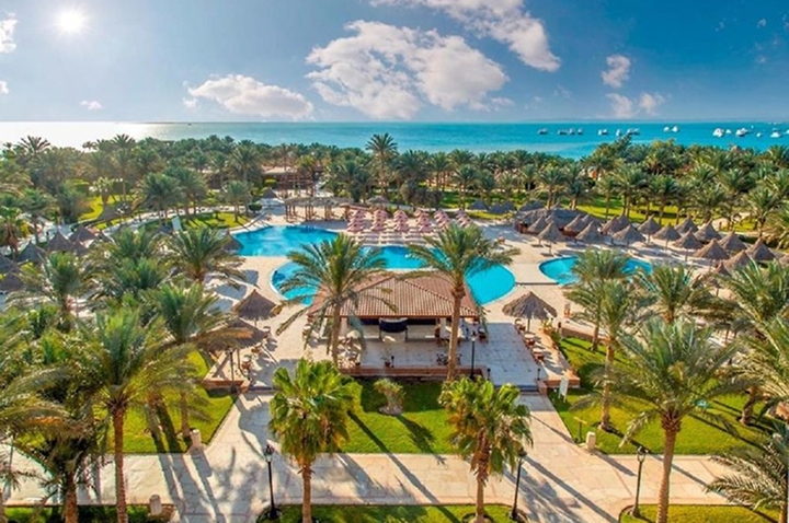 Ein malerisches Hotel, umgeben von Palmen und einem schönen Pool, bietet eine entspannende Urlaubsatmosphäre.