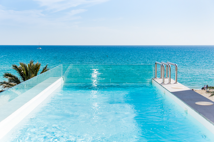 Ein Pool mit Blick auf den Ozean unter klarem, blauem Himmel – der perfekte Ort für einen Luxusurlaub.