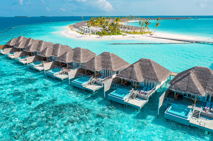 Aerialansicht eines tropischen Resorts mit charmanten Strohhütten, eingebettet in eine malerische Landschaft.
