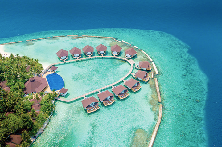 Luftaufnahme eines luxuriösen Resorts mit Bungalows auf einer malerischen Insel, umgeben von türkisblauem Wasser.