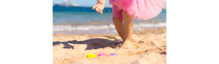 Ein Baby sucht fröhlich nach Ostereiern am Strand