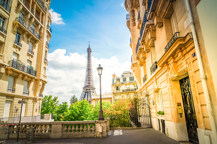 Blick auf den Eiffel-Turm von einer schmalen Straße in Paris, die typisch für die Stadt ist.
