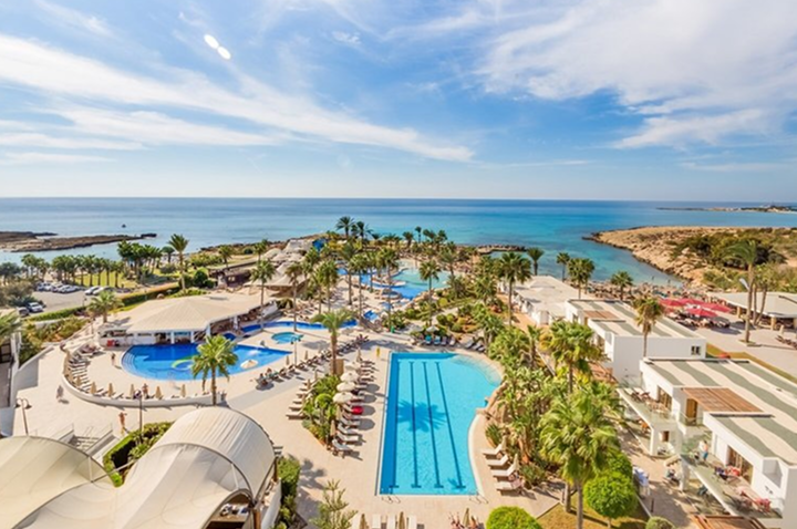 Luxuriöses Hotel mit Poolbereich am Strand, umgeben von Palmen und direktem Zugang zum Meer.
