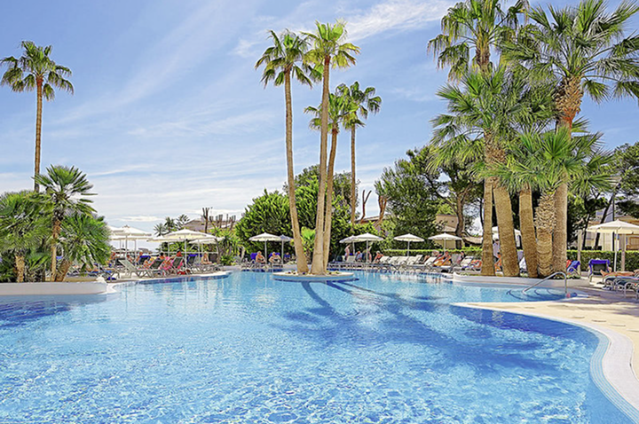 Ein großer Pool im Hotel, umgeben von Palmen und Sonnenliegen, ideal zum Entspannen und Sonne tanken.