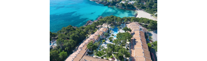 Luftaufnahme des Resorts mit Blick auf den Strand und das Hotel, umgeben von Palmen und klarem Wasser