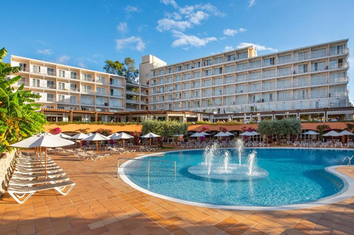 Hotelpool und Loungebereich am Strand, umgeben von Liegen und Palmen, ideal zum Entspannen und Genießen der Sonne.