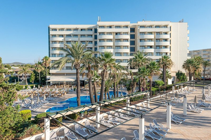 Ein Hotel umgeben von Palmen mit einem einladenden Swimmingpool im Vordergrund