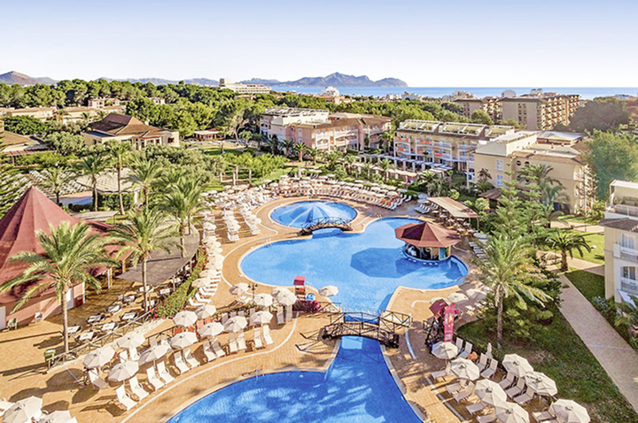 Großes Hotel mit einem einladenden Pool und bequemen Sonnenliegen für entspannte Tage am Wasser.
