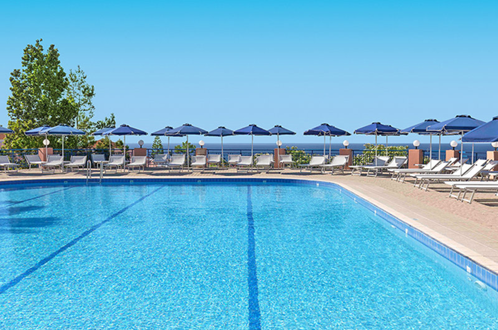 Hotelpool in Rhodos mit strahlend blauem Wasser und weißen Sonnenschirmen, perfekt für einen Urlaub am Wasser.