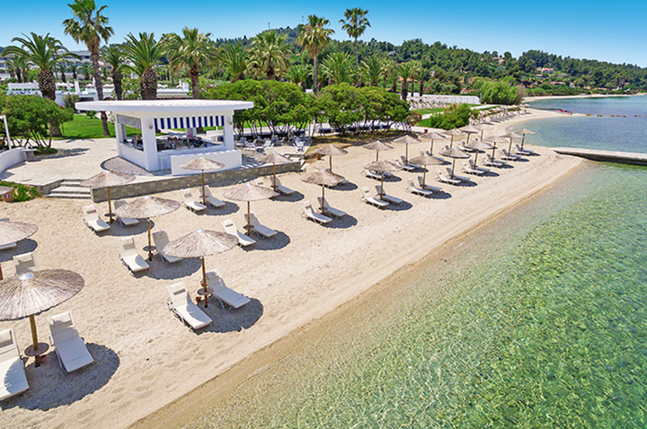 Ein sonniger Strand mit bunten Sonnenschirmen und Liegen auf dem goldenen Sand.