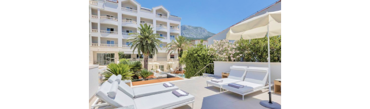 Heller Patio mit weißen Möbeln und einem Sonnenschirm, ideal für Entspannung im Hotel in Kroatien