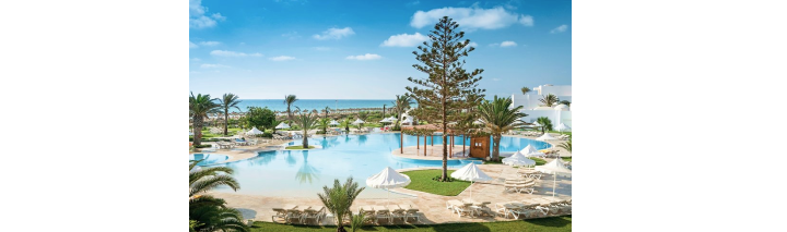 Blick auf den Pool des Strandclubs im tunesischen Hotel, umgeben von Sonnenliegen und tropischen Pflanzen.