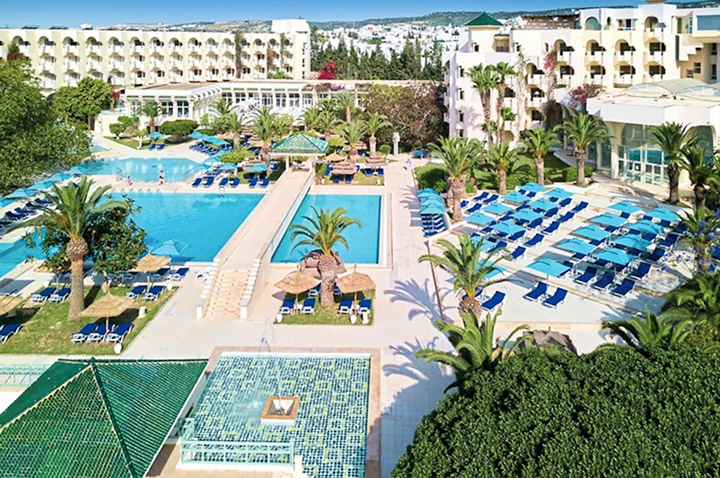 Hotelansicht mit einem einladenden Pool und Sonnenliegen für Gäste.